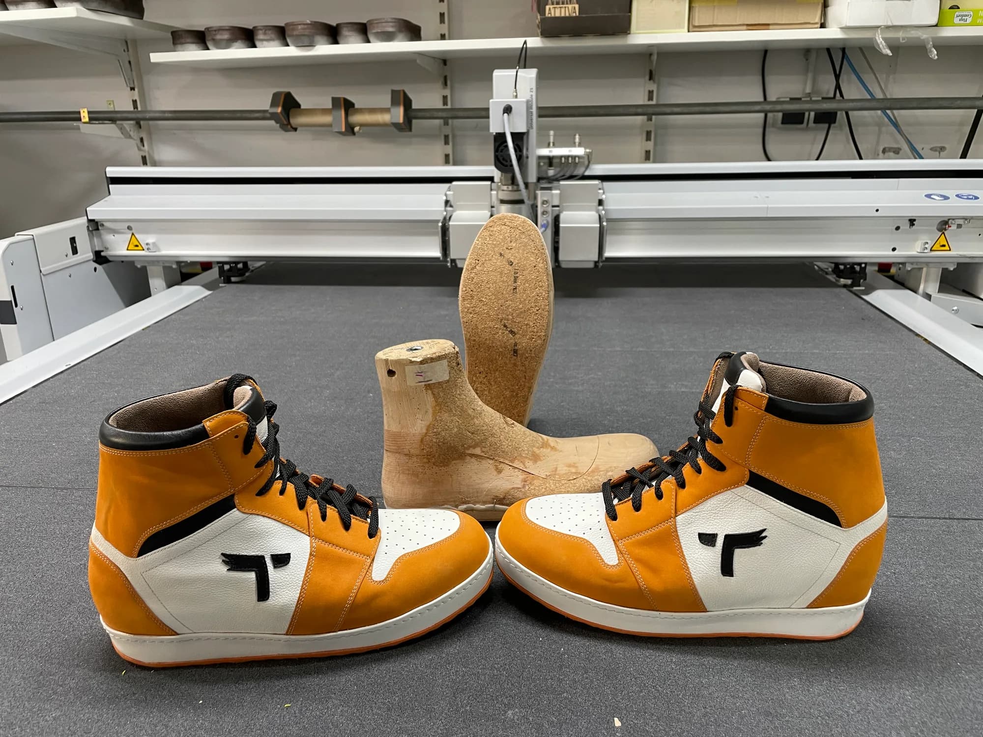Maßgefertigte Sneaker in Orange und Weiß neben Holzleisten in der Werkstatt